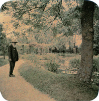 Claude Monet standing sideways, in front of waterlilies, Giverny garden